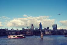 A picture of the Thames river in London, with a bird flying in the sky and a boat crossing the river.