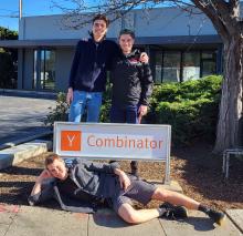 Three students in front of sign