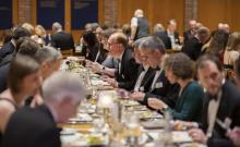 Diners sitting at a long table having dinner in the College Dining Hall