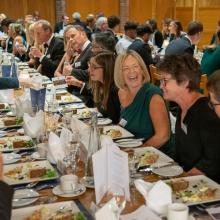 Diners sitting at a long table having dinner in the College Dining Hall