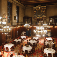 View of the Great Hall of the Merchant Taylors' Hall in London set up for a dinner with round tables